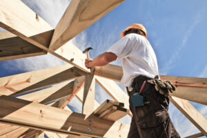 a construction worker hammering a roof frame